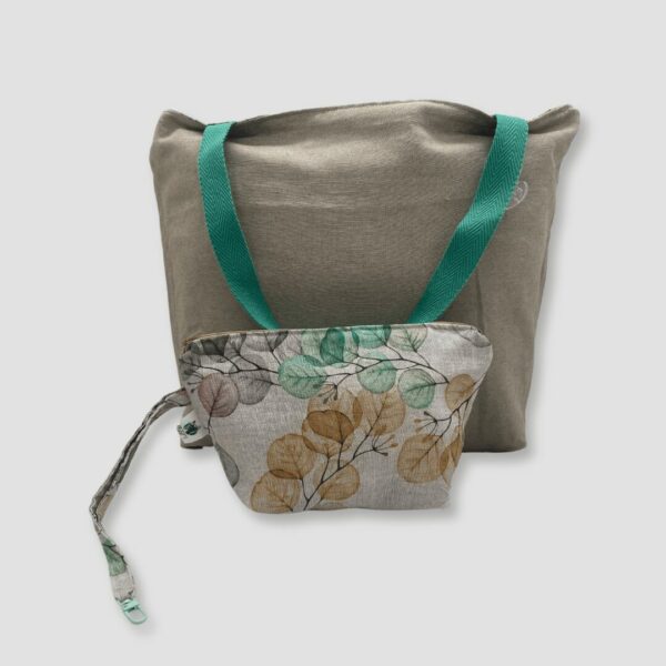 Parte interna de bolso estampado floral y colores tenues en amarillo, lila y verde con fondo blanco. El reverso es de color beige y asas a juego color verde